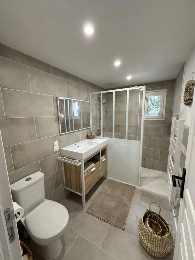 Salle de bain complète avec douche, WC, meuble vasque bois et blanc, carrelage grège grand format et spots encastrés