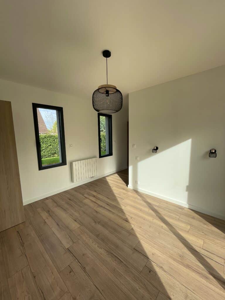 Cave à vin aménagée avec casiers bois en diagonale, présentoir central rond et cartes viticoles décoratives sur parquet clair