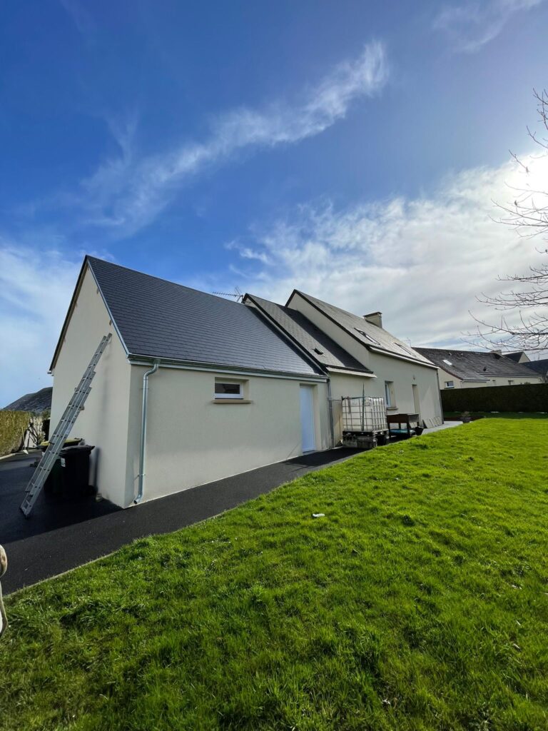 Maison rénovée avec façade enduite blanche et toiture en ardoise neuve, allée en enrobé noir et pelouse verdoyante