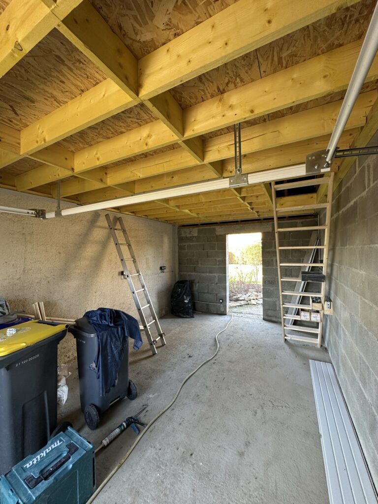 Intérieur de garage en construction avec charpente bois et escalier mezzanine - GL Travaux Calvados